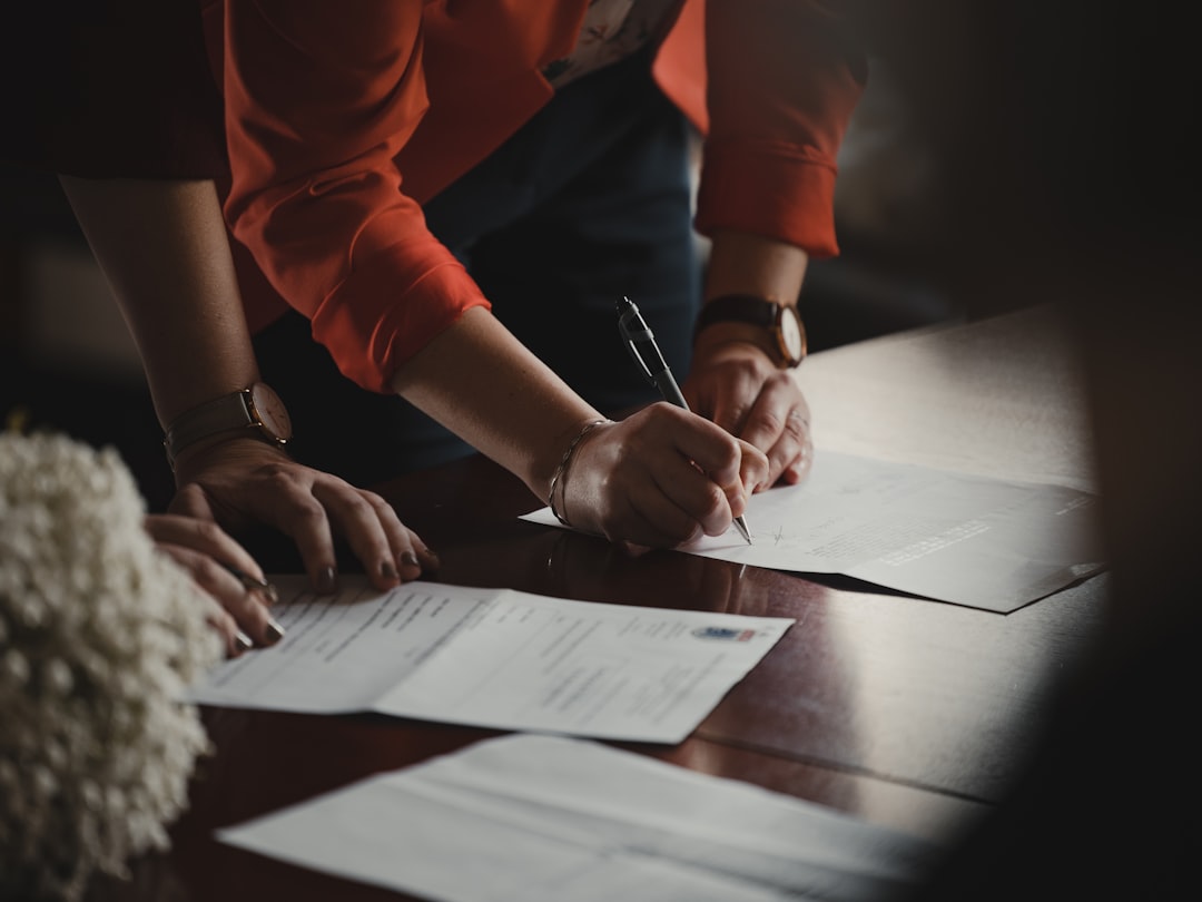 Hands signing a document representing Digihub's terms and conditions